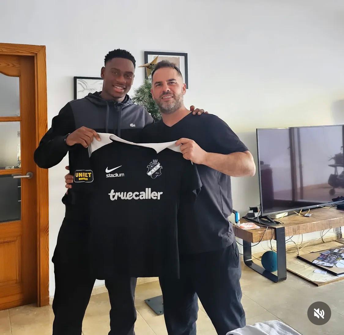 Gabriel de la Barrera junto a un futbolista al que atiende, sosteniendo su camiseta de equipo
